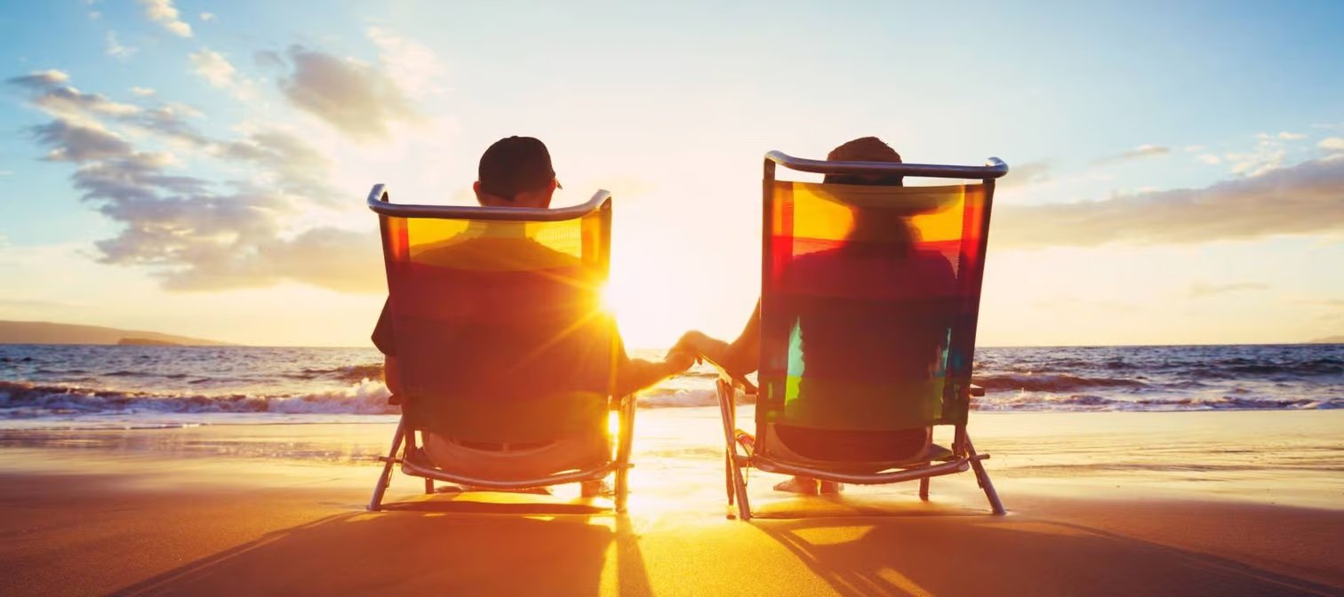 Couple sitting in chairs on the beach looking at the ocean